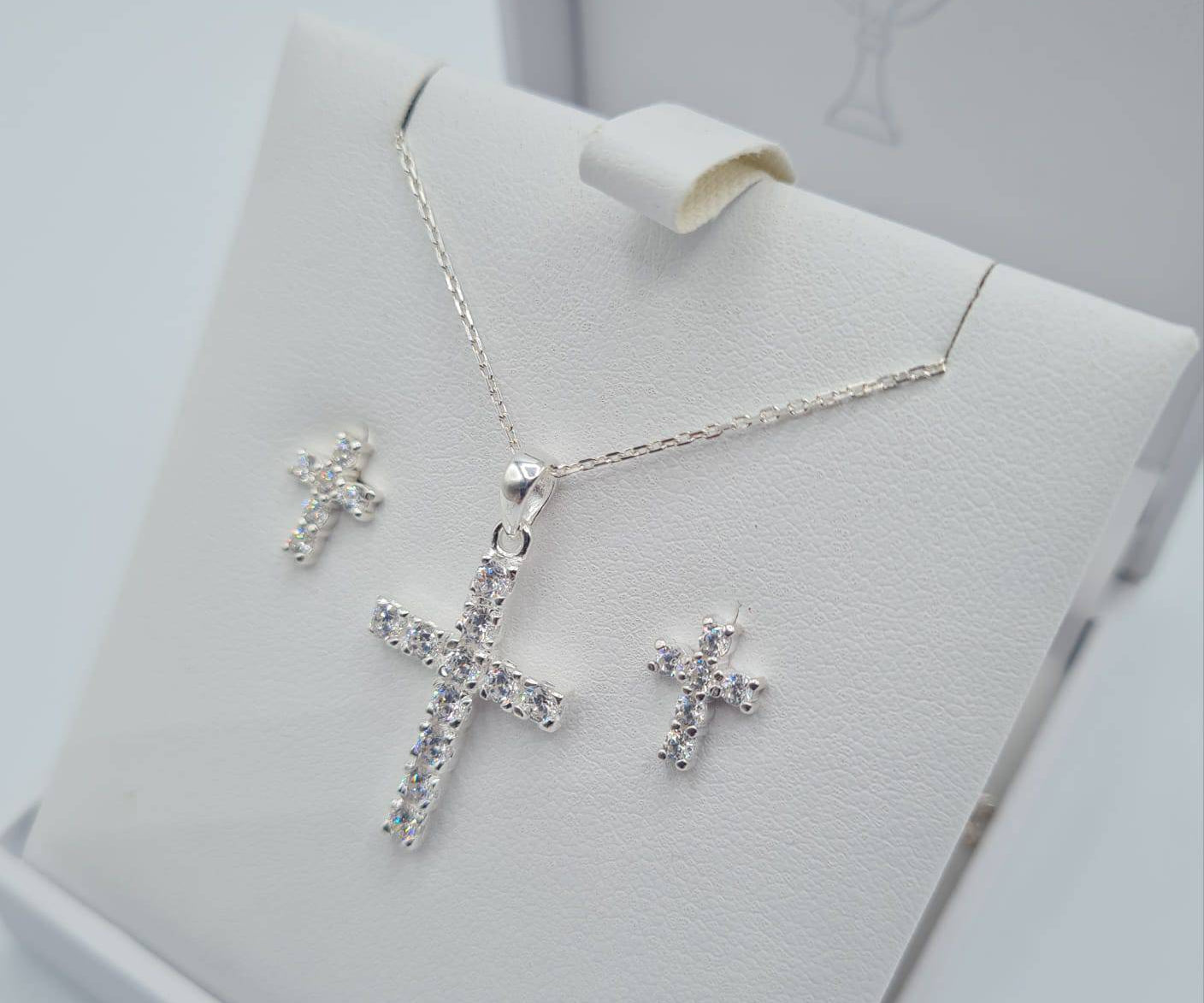 Close-up of sterling silver CZ cross pendant and cubic zirconia earrings for Holy Communion